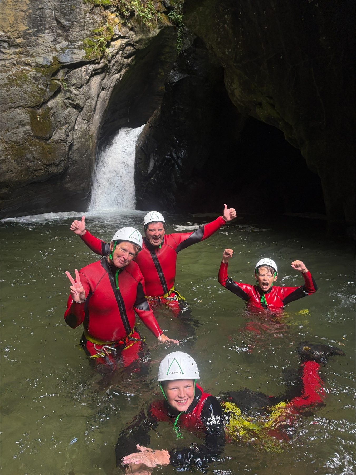 Gruppe steht bis zur Hüfte im Wasser vor einer Felswand und jubelt