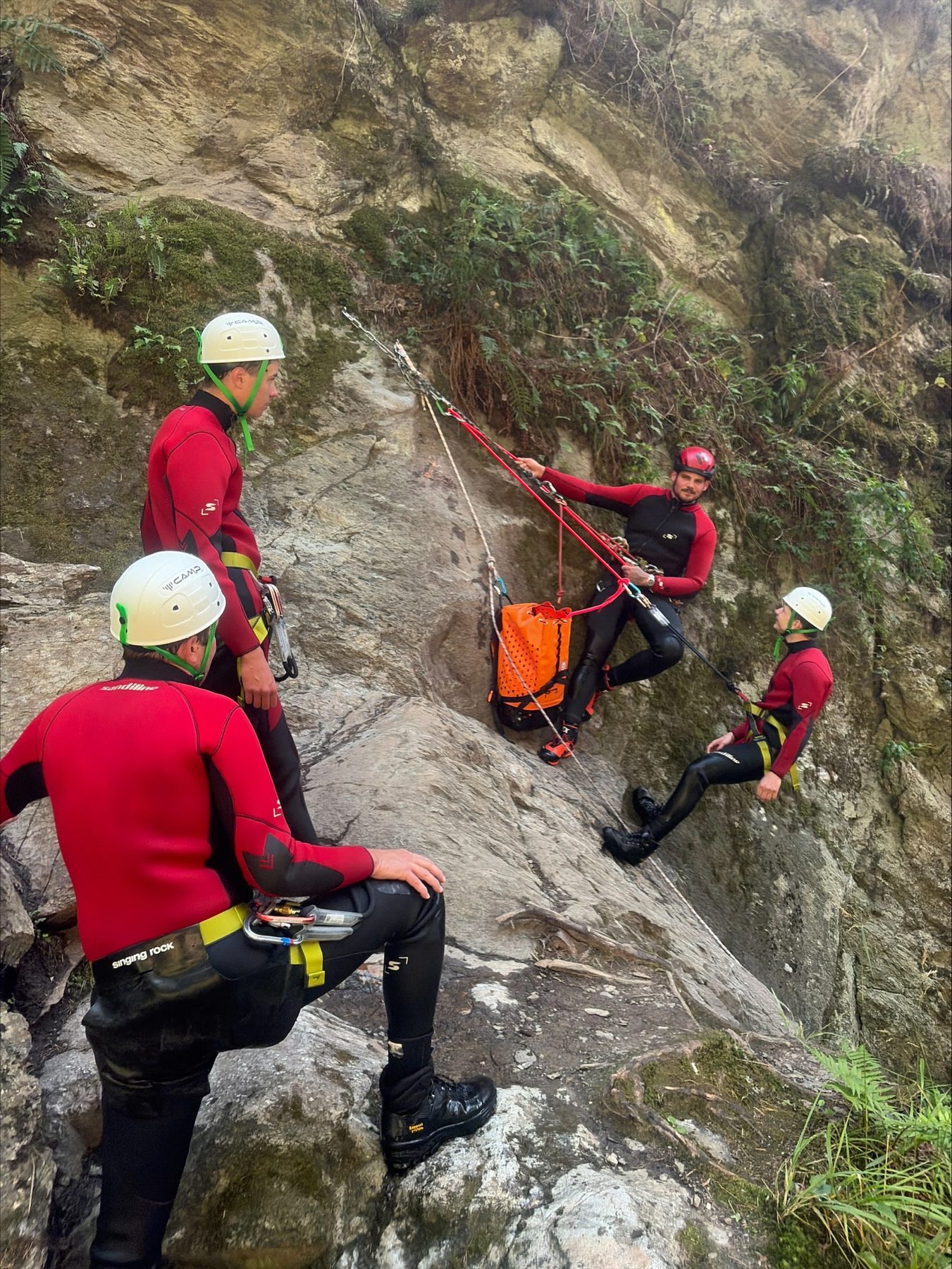 Guide und Gäste sitzen zur Einweisung auf Felsblöcken über der Schlucht
