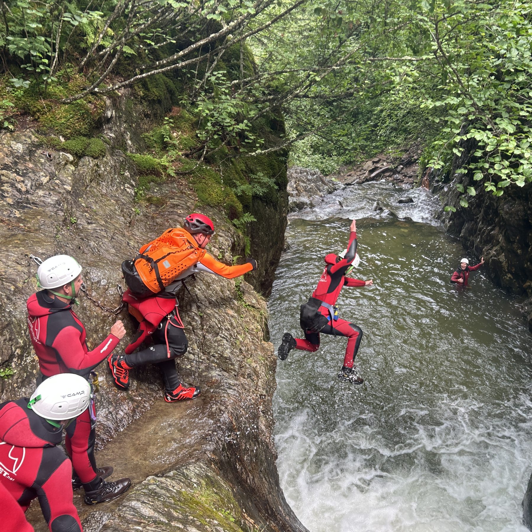 Gruppe klettert an einer Felsstufe neben strömendem Wasser abwärts